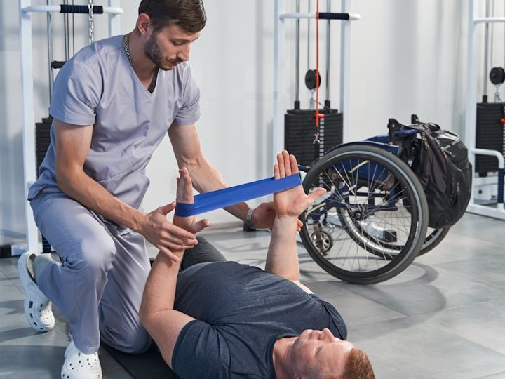 Ein Physiotherapeut hilft einem Patienten bei einer Rehabilitationseinheit auf dem Boden.