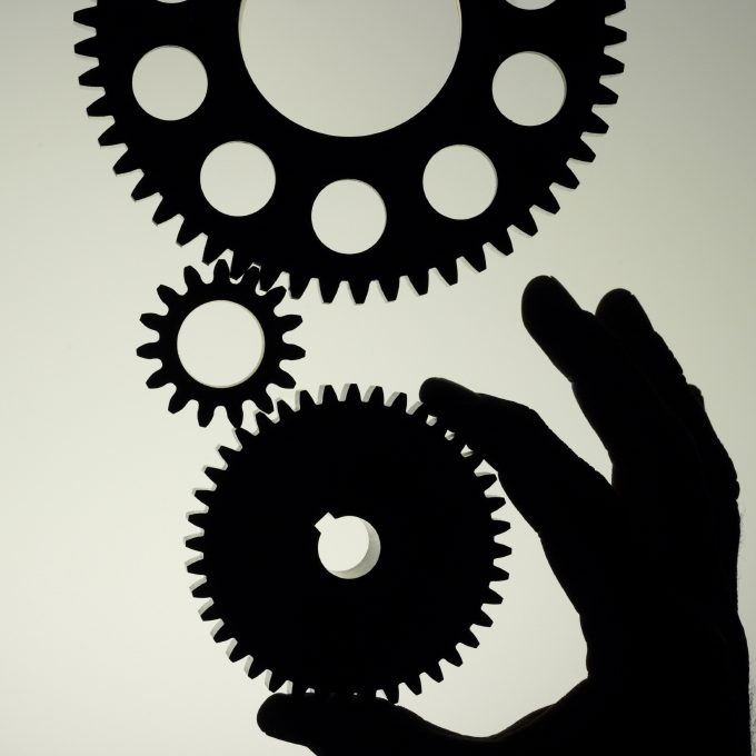 Symbolisch stehen die Zahnräder für die unterschiedlichen Branchen und Tätigkeitsbereiche aus denen wir unsere Erfahrungen beziehen. Das positionieren von Hand bezieht sich auf die individuelle Anordnung und Verwendung unserer Erfahrungen um den besten Service für den Kunden bieten zu können.